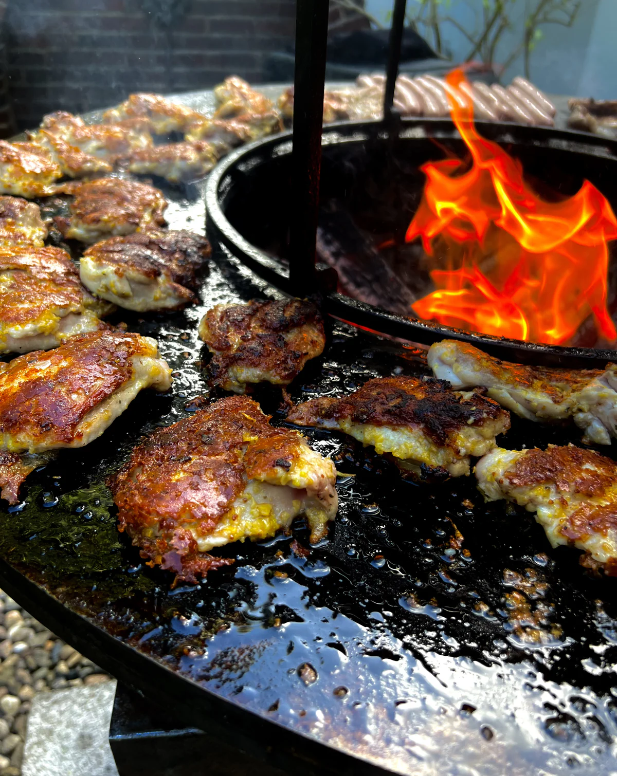 Fleisch gart auf der Feuerplatte neben offenen Flammen